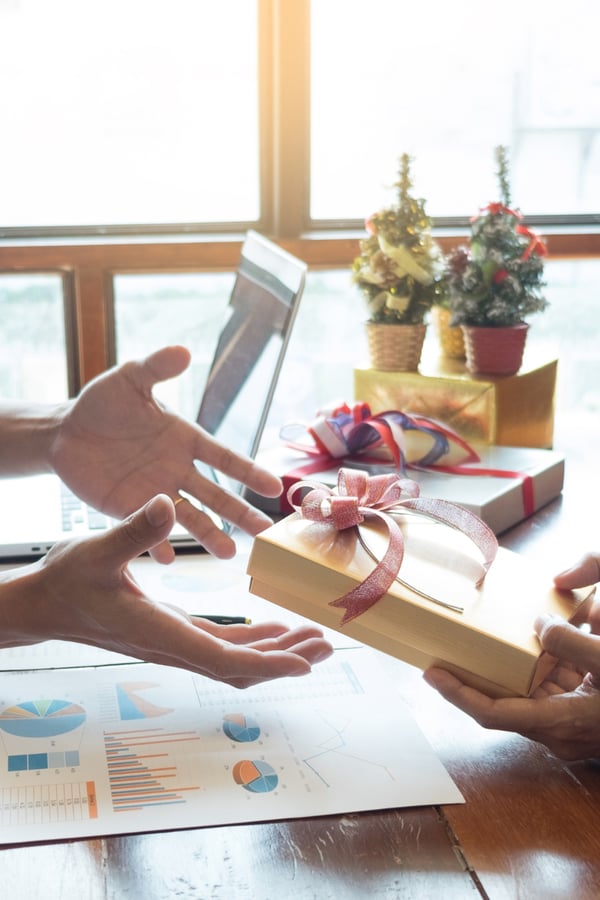 two co-workers exchanging christmas gifts. 