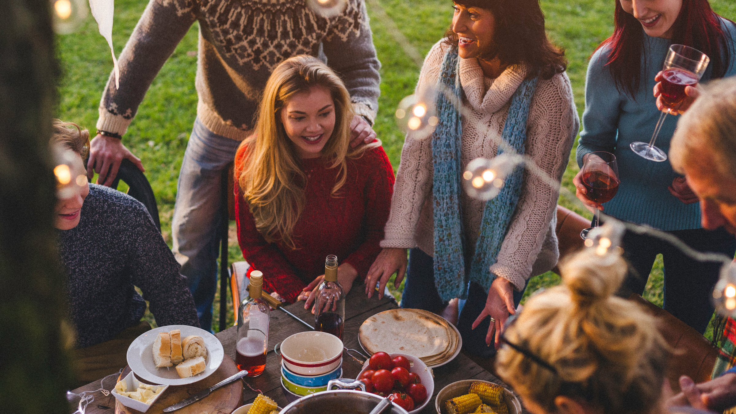 A community have gathered for a meal in a field.