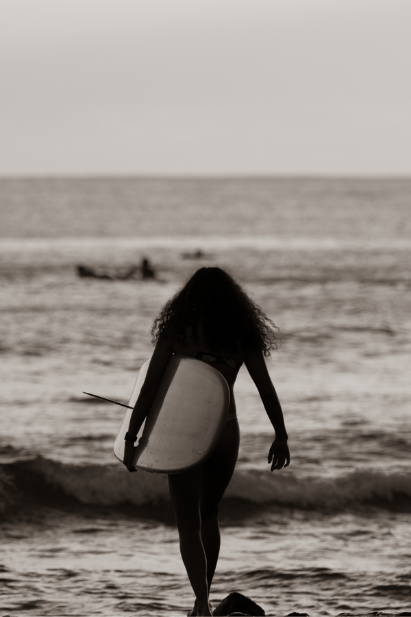Someone walking out to sea carrying a surfboard. 