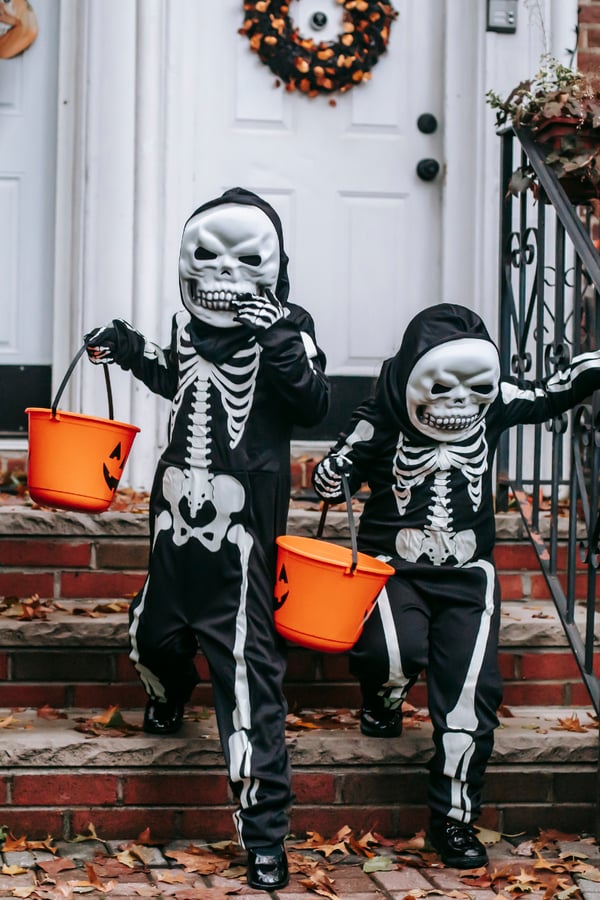 Two kids dressed up as skeletons to go trick-or-treating.