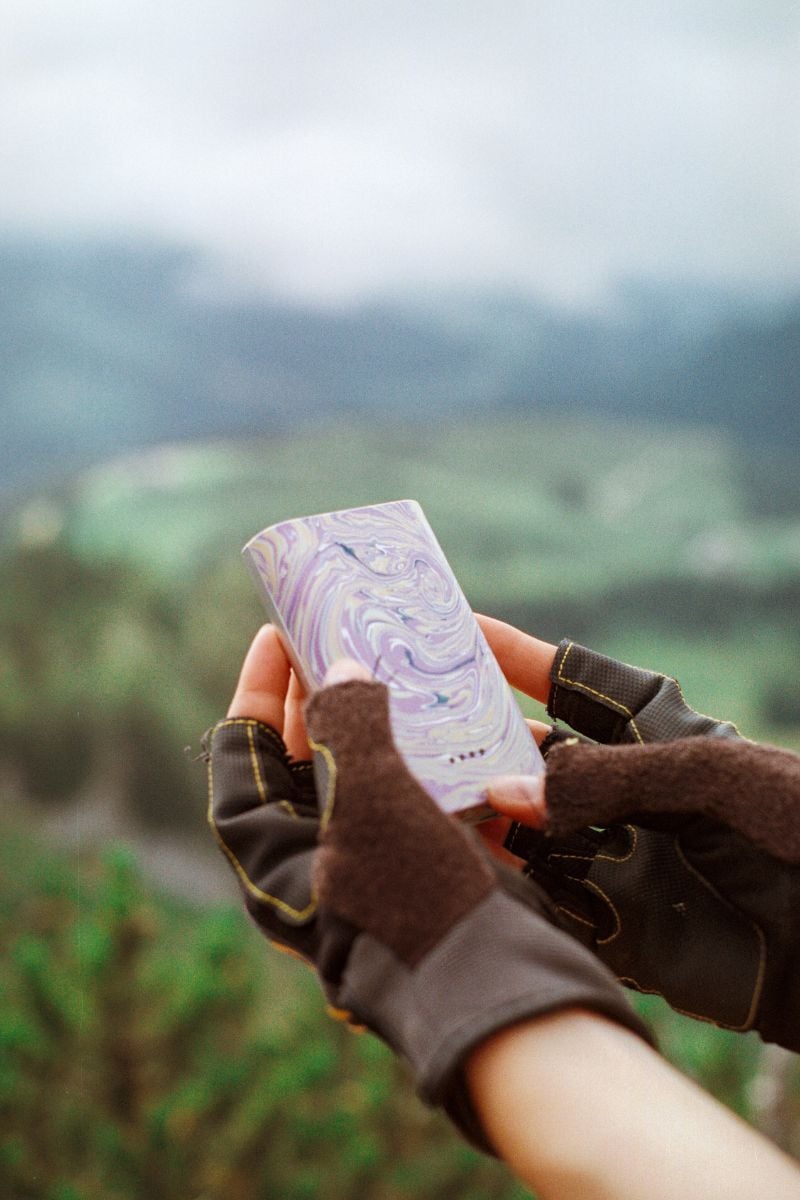 Hands holding a Gomi powerbank whilst out on a hike.