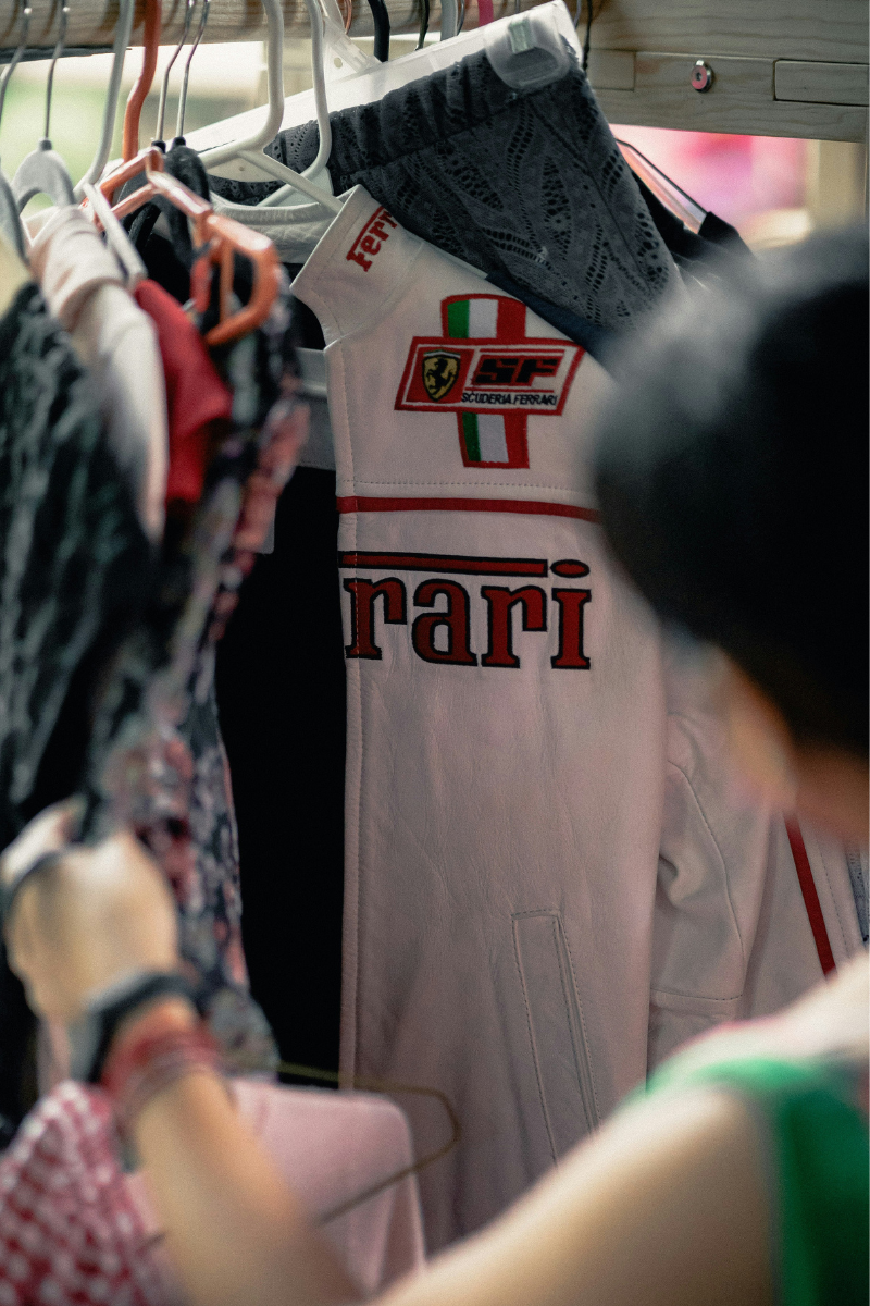 A photo of someone looking through a rail of clothes and a white Ferrari-branded jacket is visible.