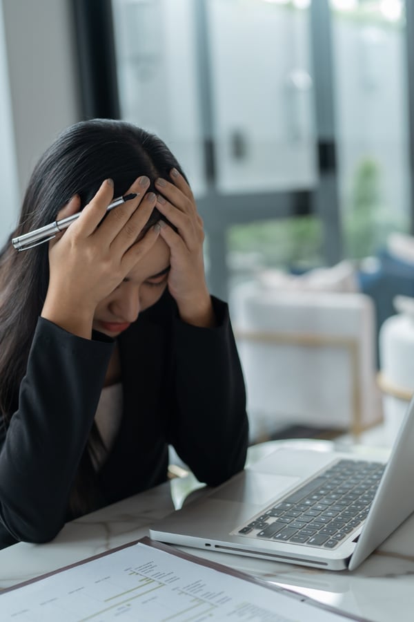 Someone looking very stressed with their hands on their head in an office.