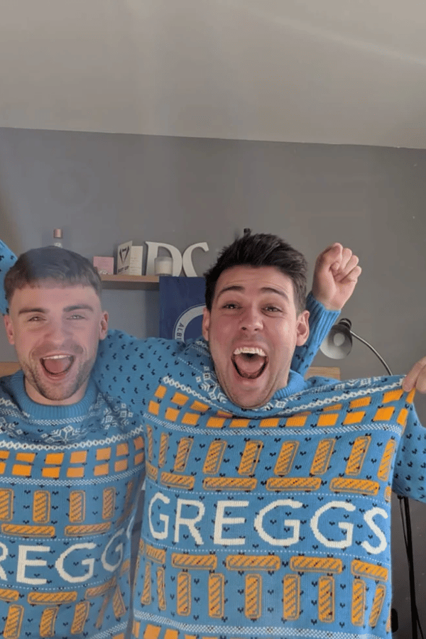 Two people wearing Greggs branded Christmas jumpers