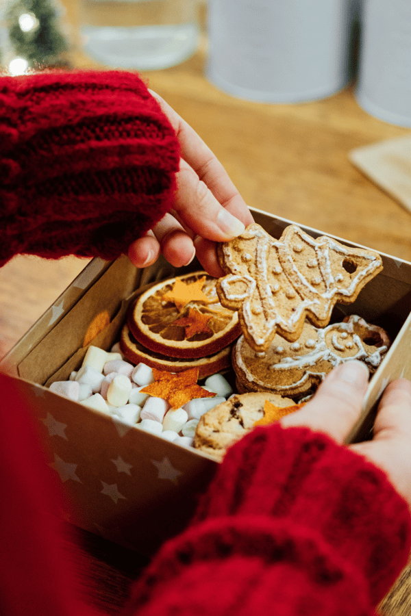 Someone packing a Christmas gift hamper with some festive Christmas cookies. 