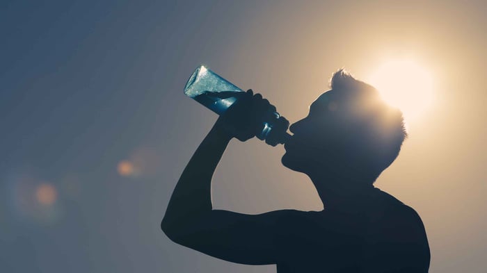 A man drinking water from a sports bottle in the summer.