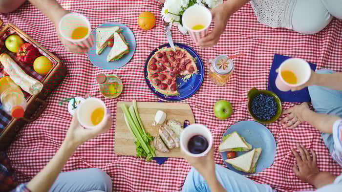 A group of friends having a picnic and using reusable cutlery.