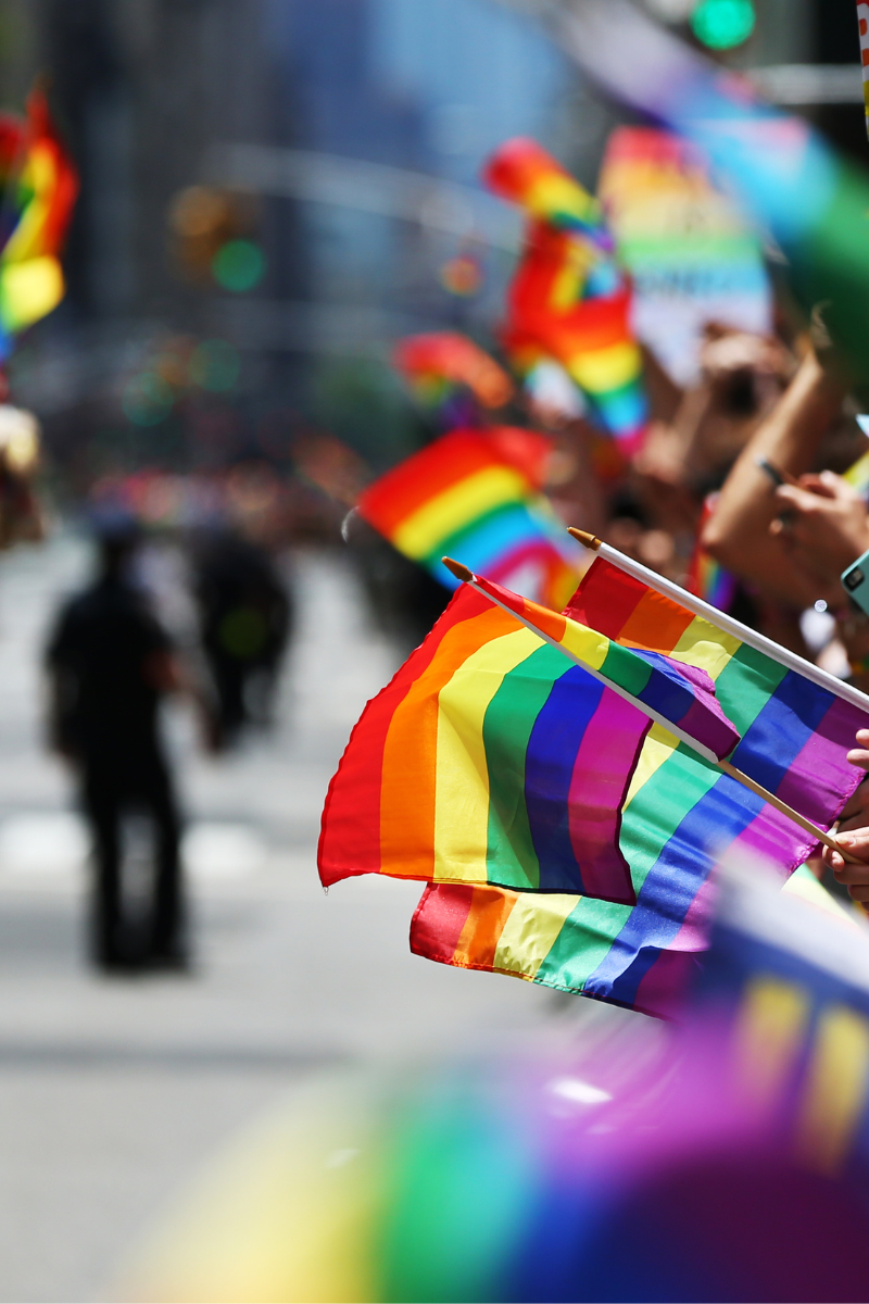 People at a Pride march waving rainbow flags 