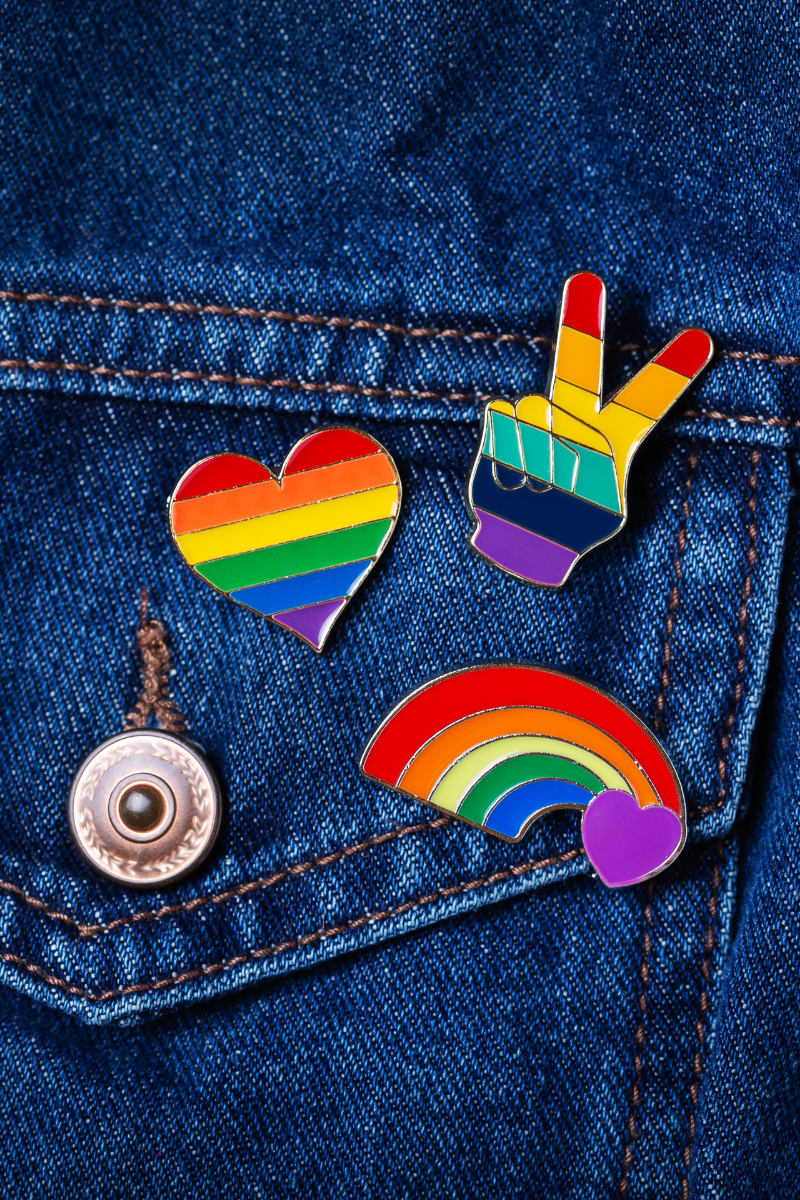 Pride rainbow badges pinned to a denim jacket.