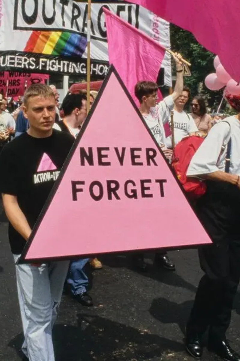 Someone holding the symbol of the Pink Triangle during a Pride march.