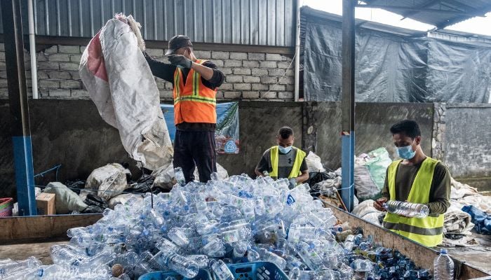 Employees at Prevented Ocean Plastic sorting through plastic bottles. 