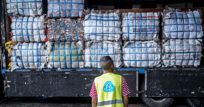 A man staring up at a truck full of plastic collected from beaches and waterways.