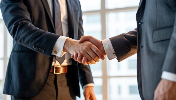 Two men in suits shaking hands. 