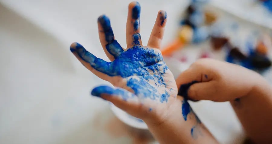 A kid's hand covered in blue paint.