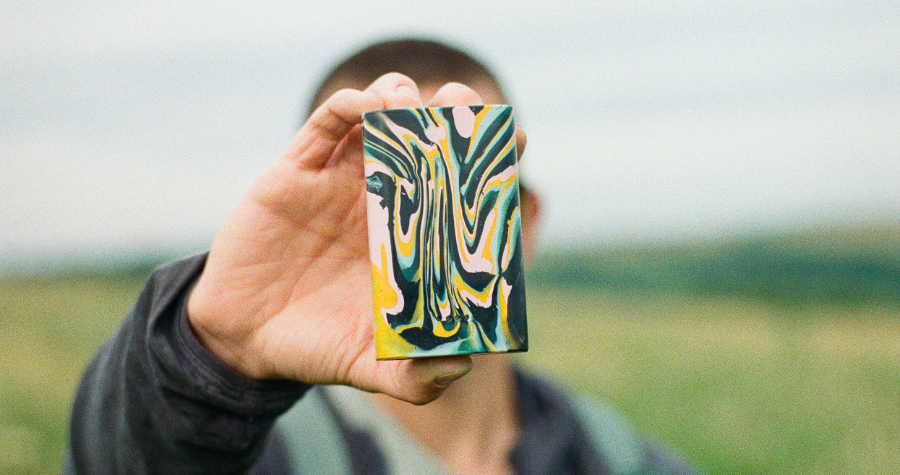 A man holding a Gomi colourful recycled plastic powerbank up to the camera.