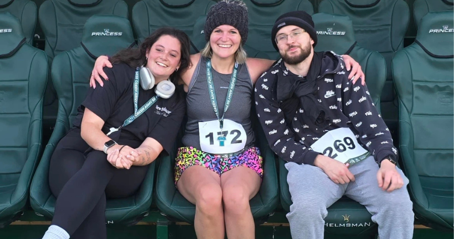 Kate, Hollie and Roy sit in the Plymouth stadium after completing the 2025 Plymouth Green Army Fun Run. 