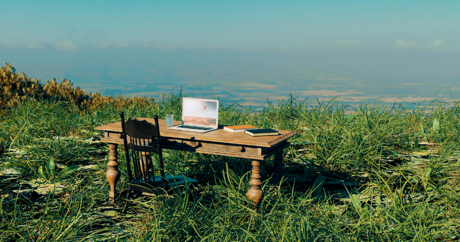 A desk outside in a field with a laptop on. 